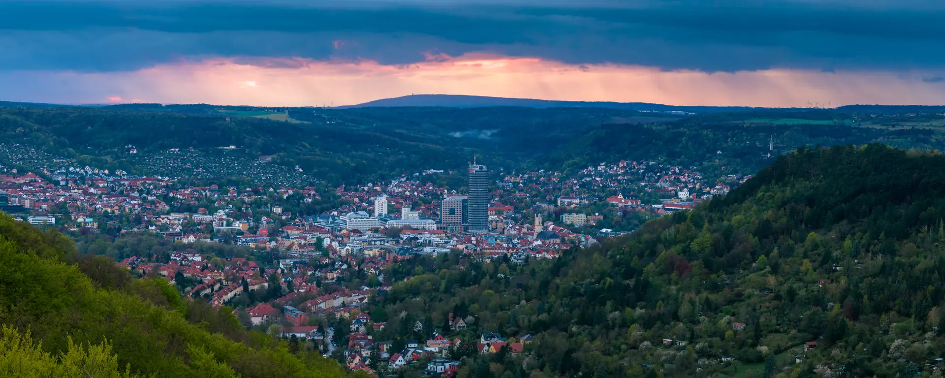 Jena zur blauen Stunde, rosa Wolken über der Stadt und den bewaldeten Hängen