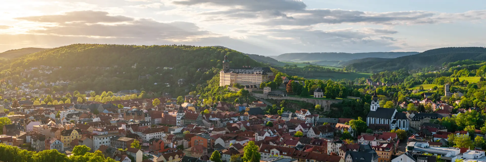 Rudolstadt mit Schloss Heidecksburg über der Altstadt, im Hintergrund bewaldete Höhen