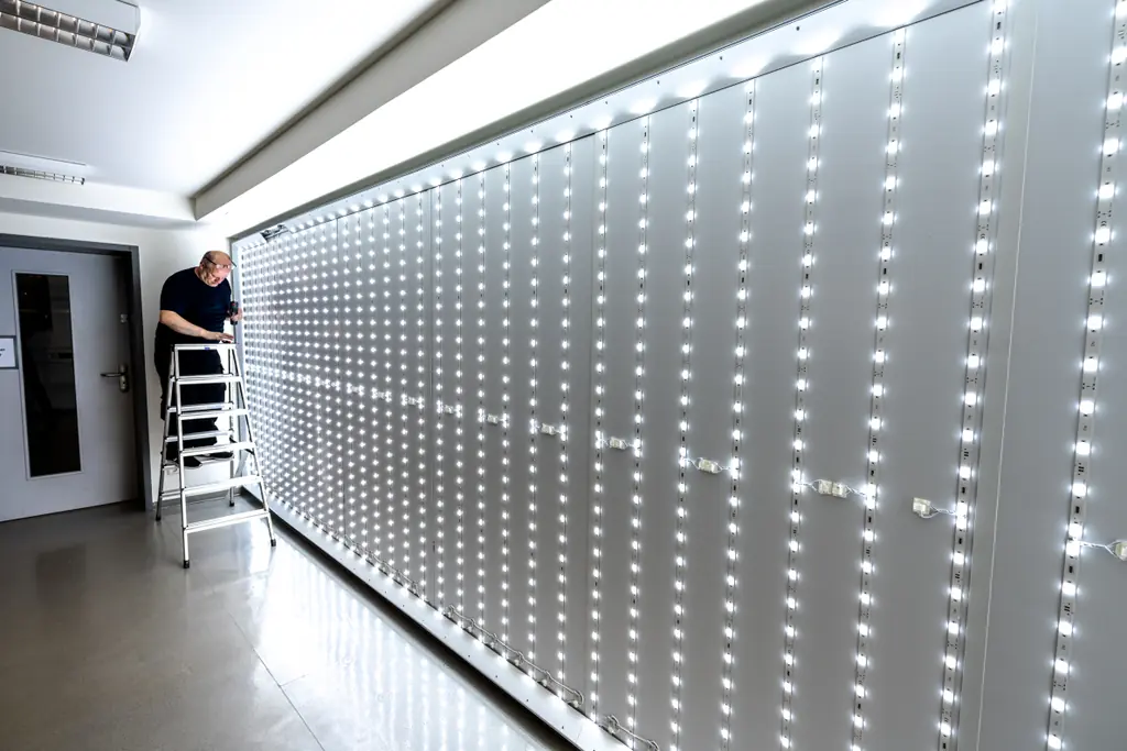 Montage der LED-Module im Aluminiumrahmen an der Kellerwand, ein Monteur richtet die Fläche aus